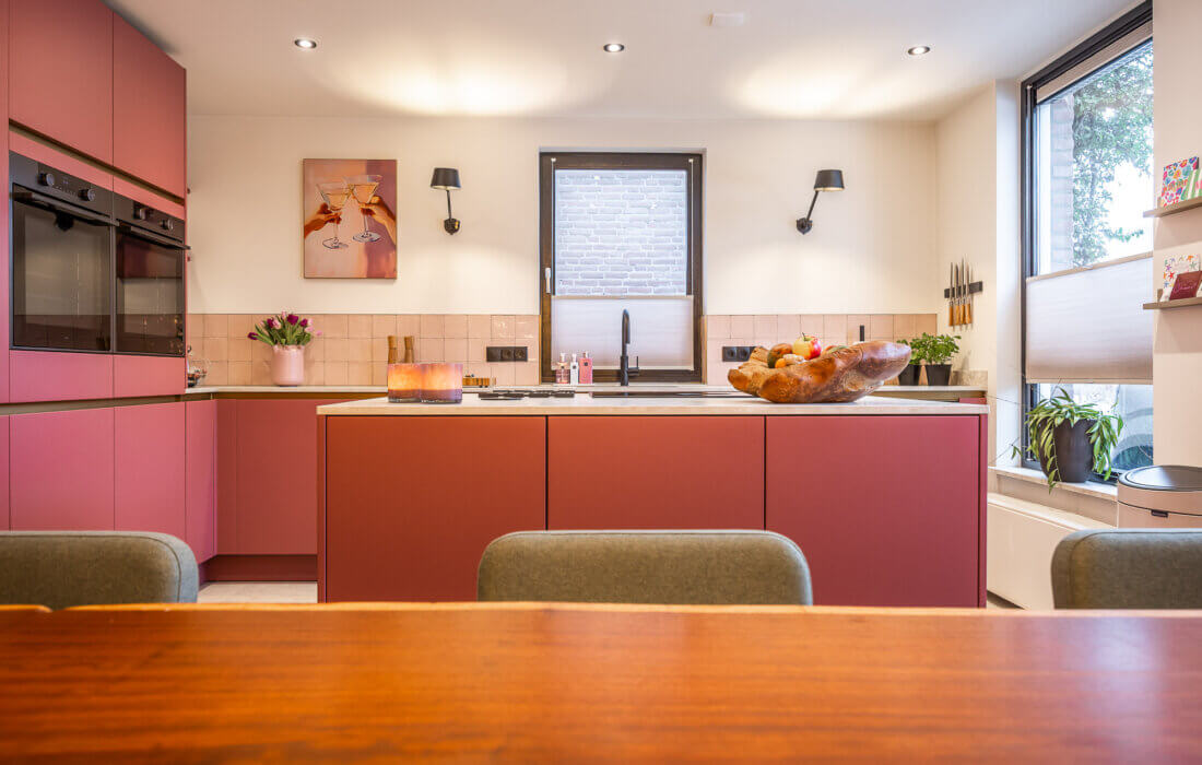 moderne greeploze L-vorm keuken met kookeiland in een roze kleur