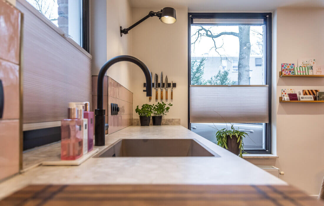 L vormige moderne keuken met keramisch werkblad en quooker kraan