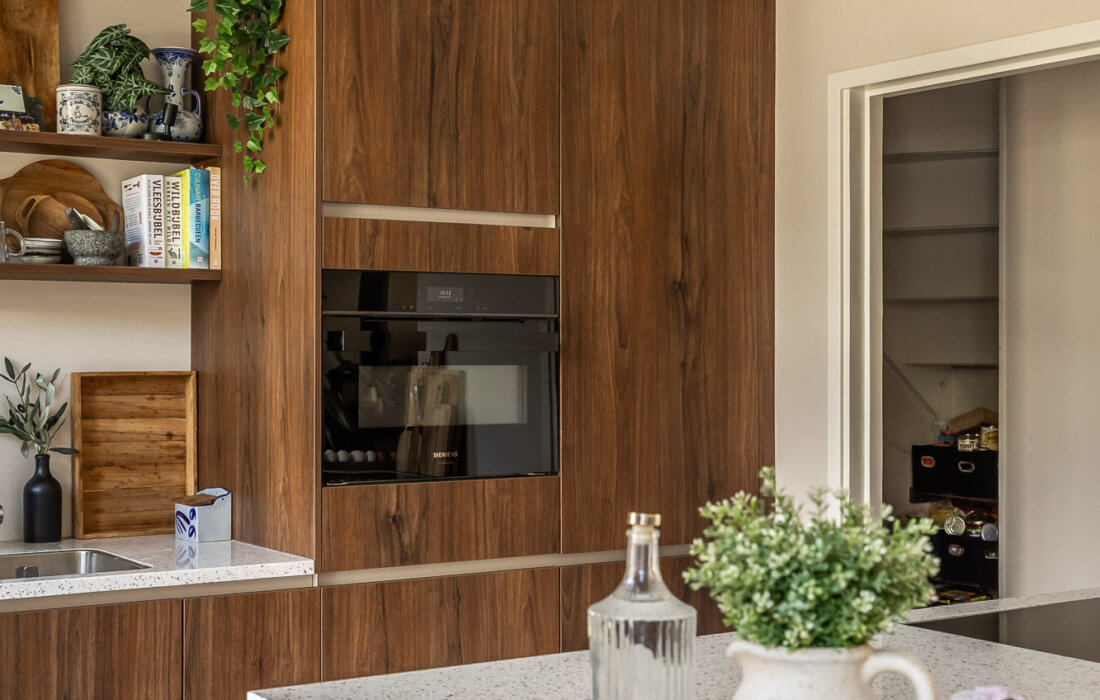 beige kookeiland met houten keukenwand en ingebouwde oven